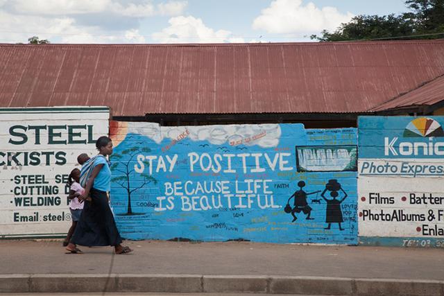 Woman with child on her back walking down the sidewalk in Zambia