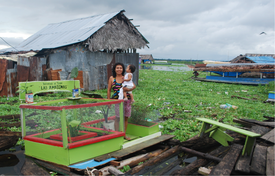 A mother holds her child in a community garden in Iquitos, Peru 