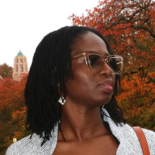 Headshot of Amanda Debuo Der looking to the right in front of trees with orange leaves.
