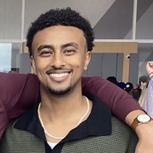 Headshot of Biruk Araya wearing a green and black striped shirt.