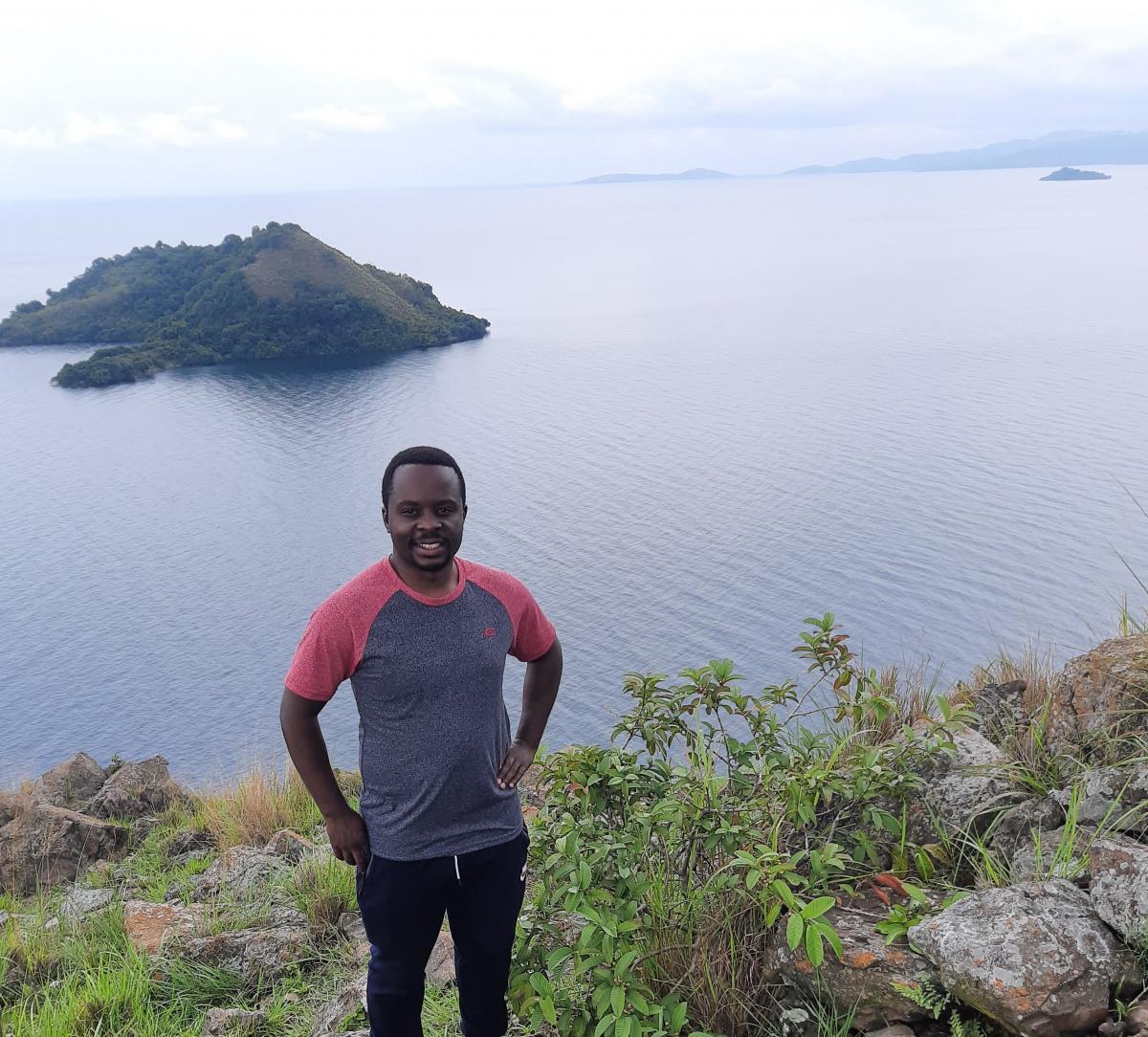 Dieudonne standing at the top of a ledge in front of a river.