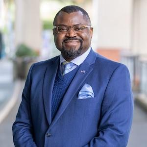 Headshot of John-Jacques Kayembe wearing a suit and tie