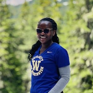 Headshot of Marilyn Nyabuti standing in front of a mountain and some trees.