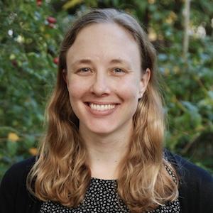 Headshot of Helen Pitchik wearing professional attire in front of greenery.