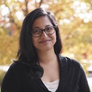 Headshot of Unmesha Roy Paladhi wearing professional attire in front of trees with orange leaves.