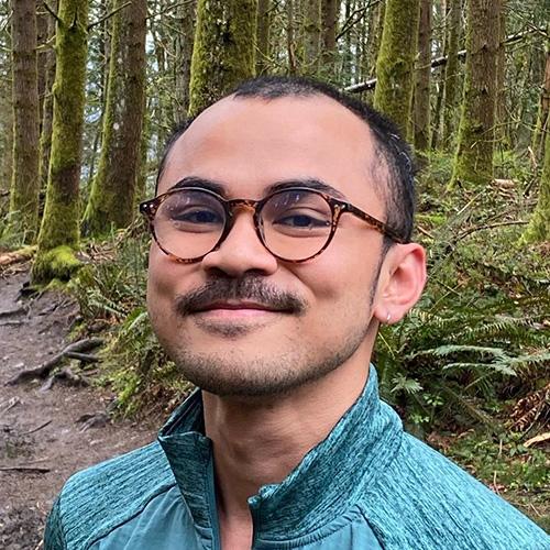 Headshot of Temy Ramadan in a green shirt in the forest. 